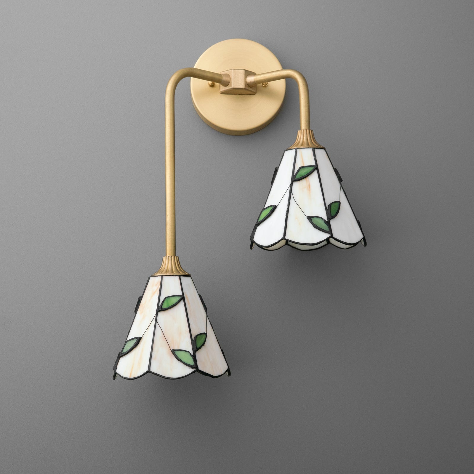 Brass-finished 2-bulb wall sconce with curved arms and stained glass shades featuring green leaf designs. - SCONCE MODEL NO. 8593
