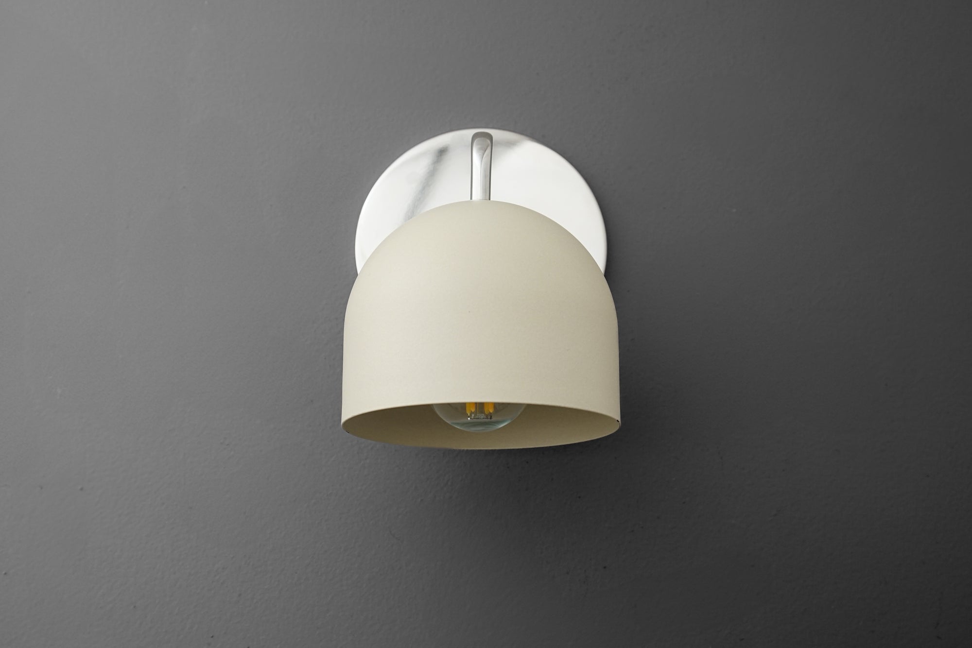 Wall sconce with polished nickel base and smooth cream dome shade against gray background. - SCONCE MODEL NO. 9436