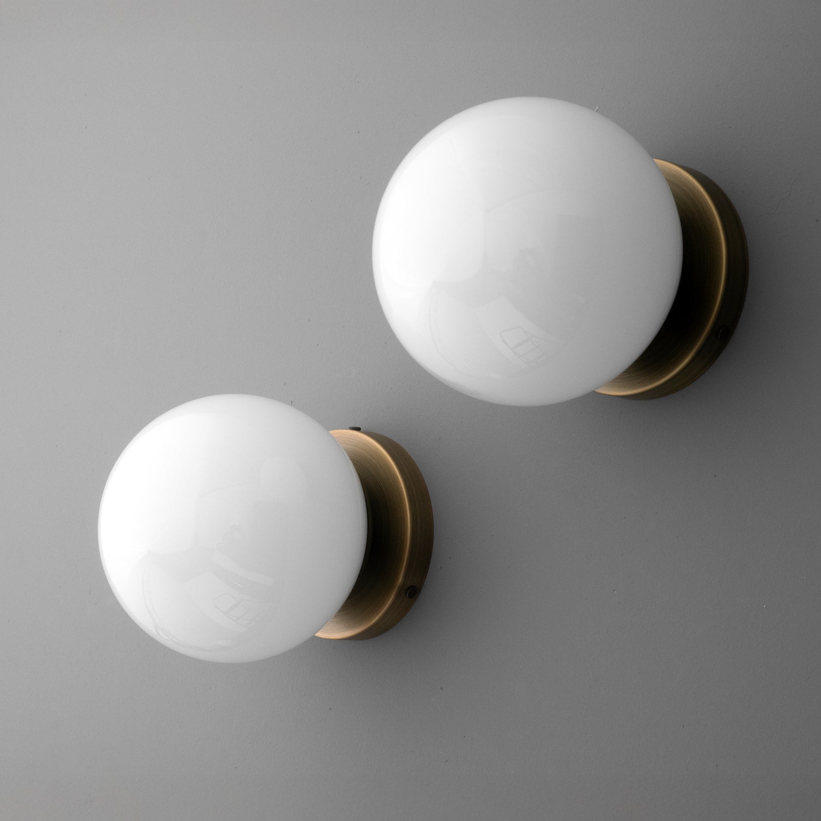 Two white glass globe sconces with round antique brass wall mounts on a gray background. - SCONCE MODEL NO. 3825