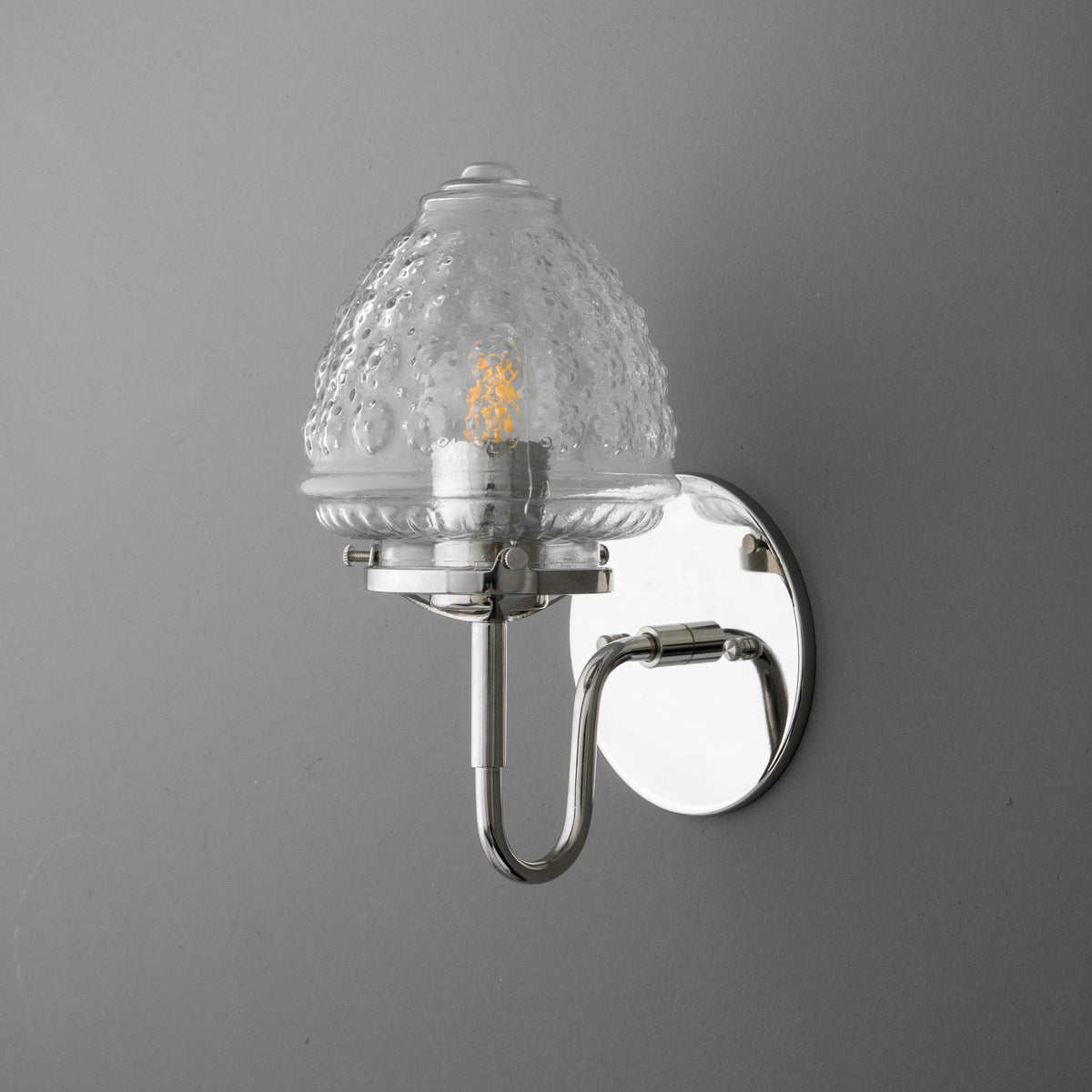 Wall-mounted single-bulb sconce with a textured clear glass shade and polished chrome base. - SCONCE MODEL NO. 1037