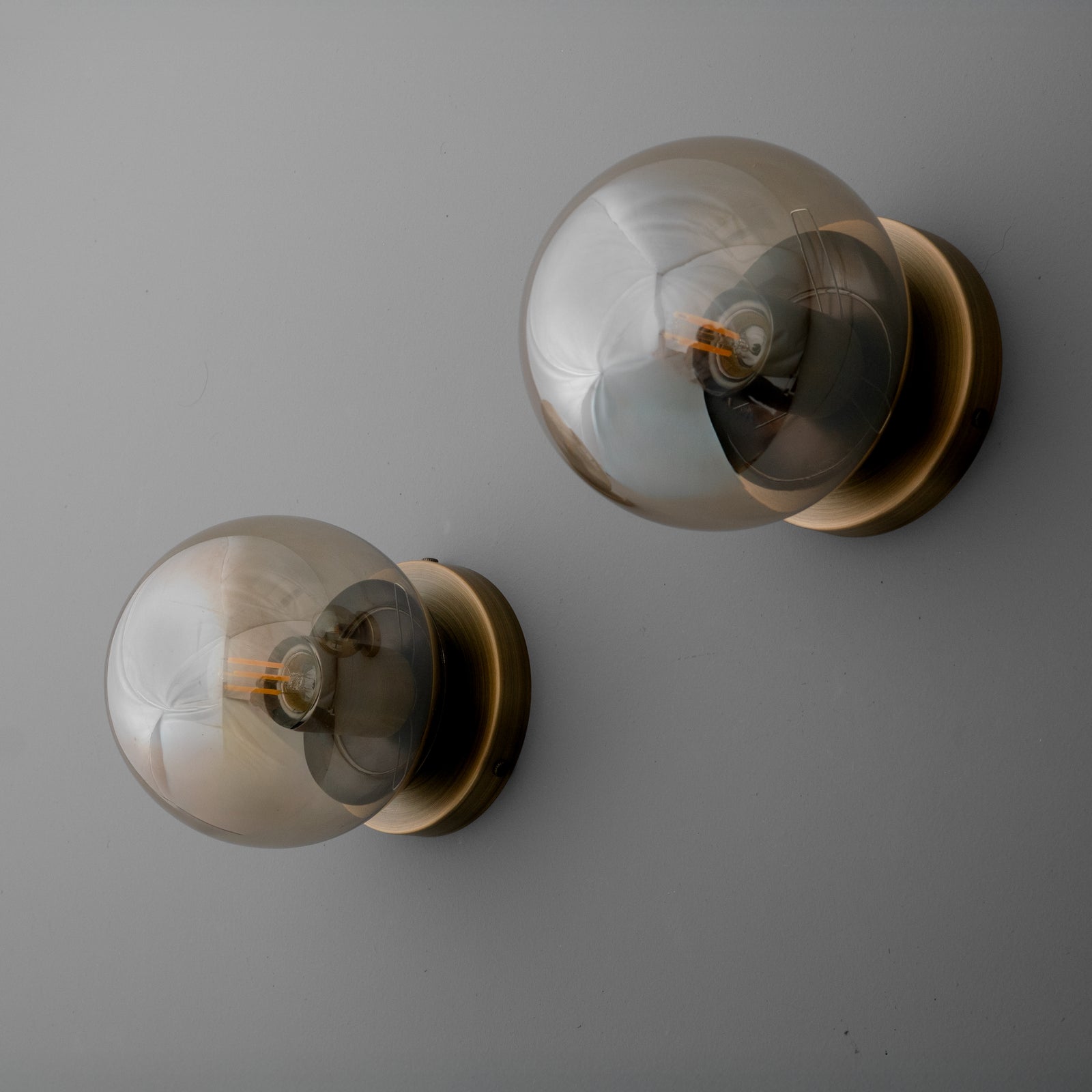 Pair of wall sconces with round smoked glass globes and antique brass bases, modern style. - SCONCE MODEL NO. 1030