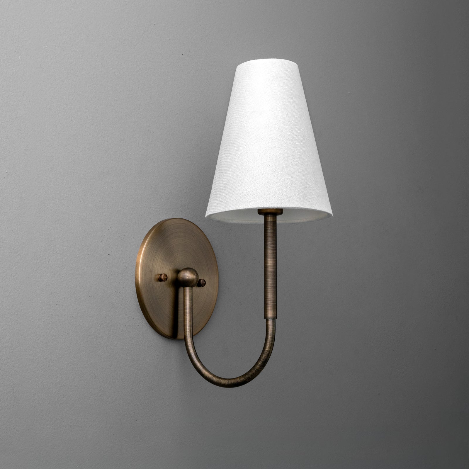 Antique brass wall sconce with curved arm and tapered white fabric shade. - SCONCE MODEL NO. 4594