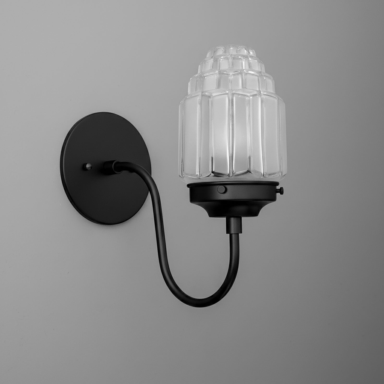 Black metal wall sconce with curved arm and clear ribbed glass shade in a dome shape. - SCONCE MODEL NO. 1074