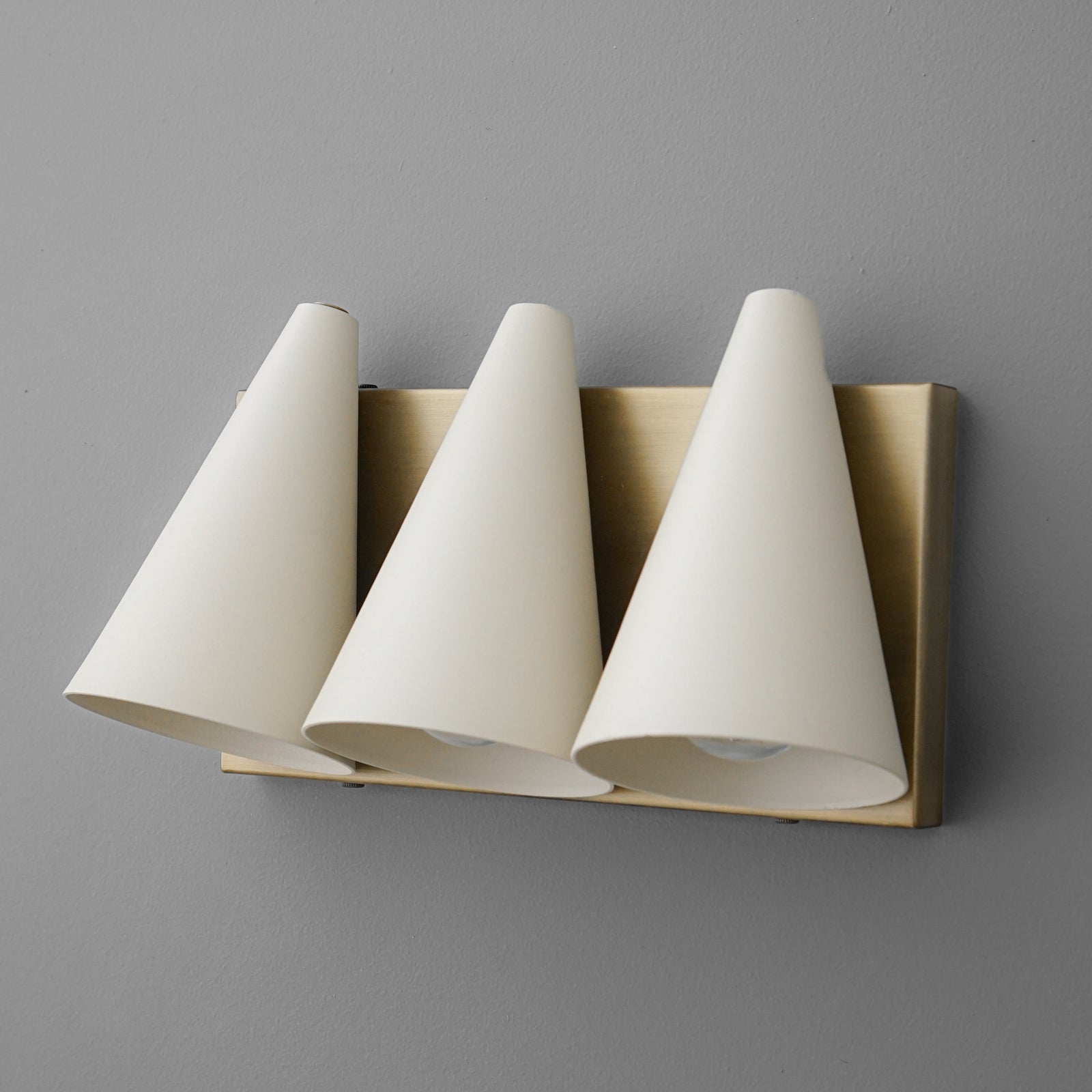 Three white conical shades mounted on a rectangular brass base vanity light fixture. - VANITY MODEL NO. 2330
