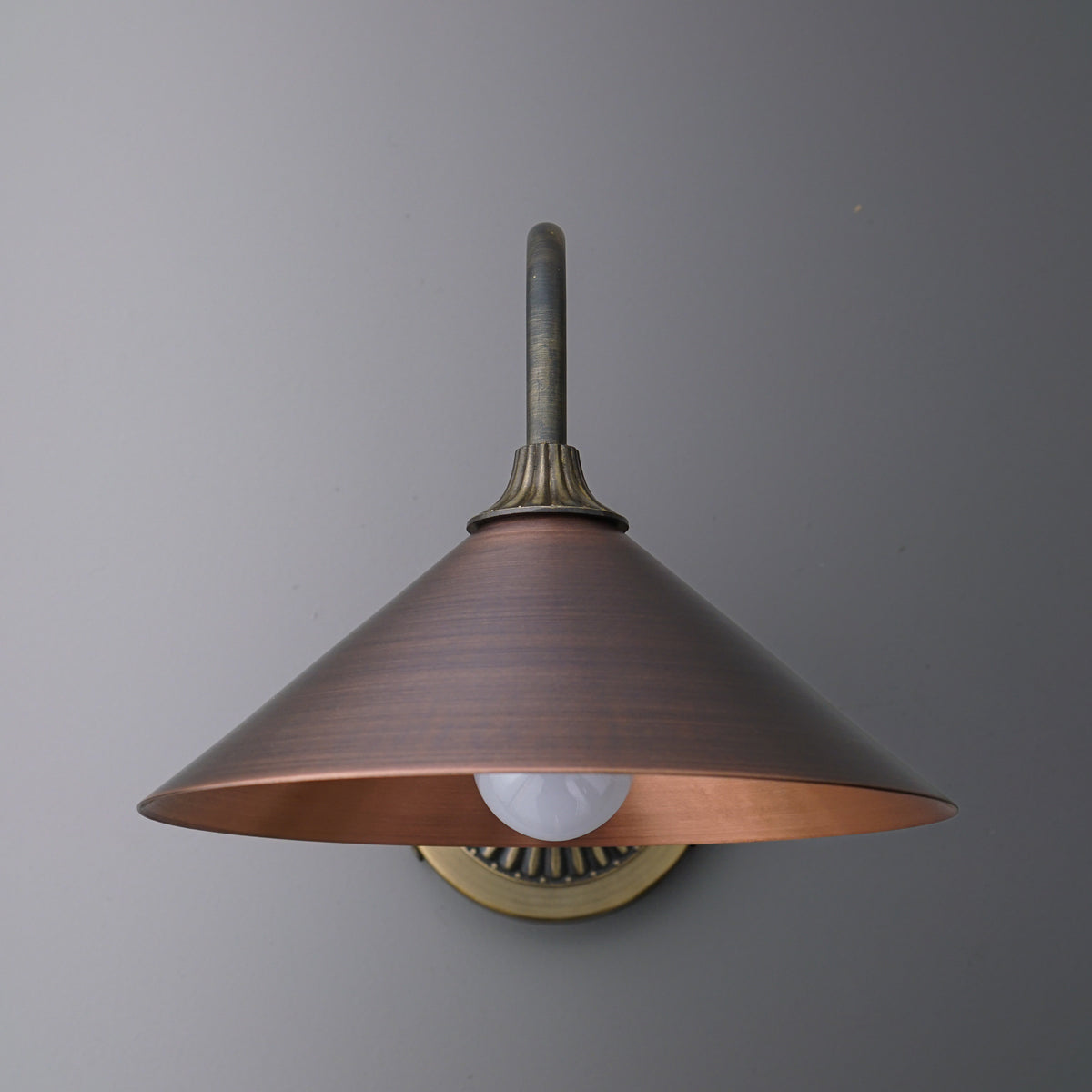 Wall-mounted sconce with a wide conical metal shade in matte bronze and an exposed bulb beneath. - SCONCE MODEL NO. 1055