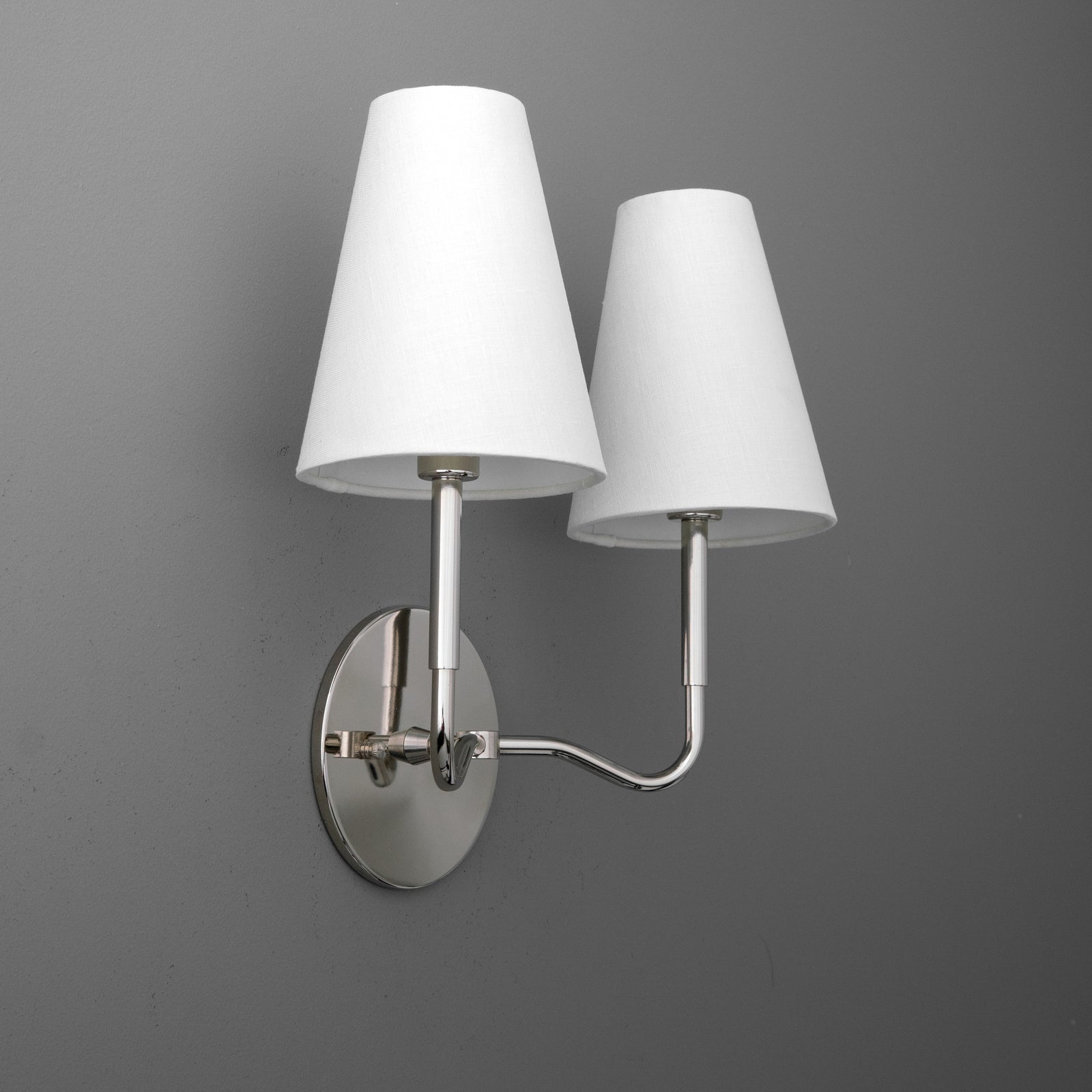 Double-bulb wall sconce with brushed metal base and curved arm, featuring white tapered fabric shades. - SCONCE MODEL NO. 9045