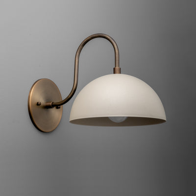 Wall sconce with raw brass finish and smooth white dome-shaped shade mounted on curved arm. - SCONCE MODEL NO. 9092