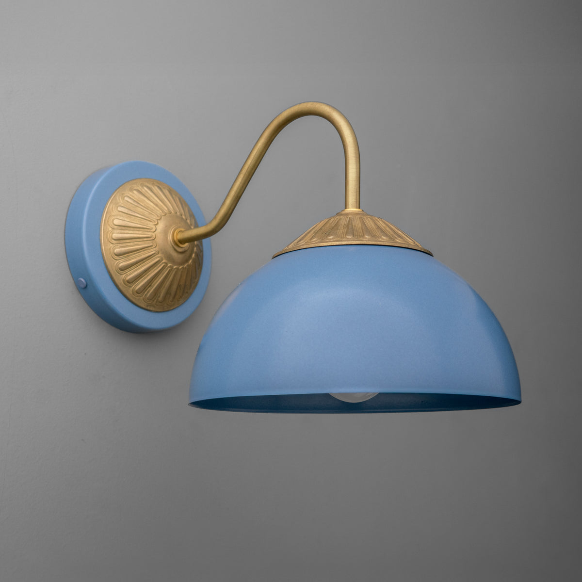 Raw brass sconce with a curved arm and periwinkle blue dome shade against a gray wall. - SCONCE MODEL NO. 9408