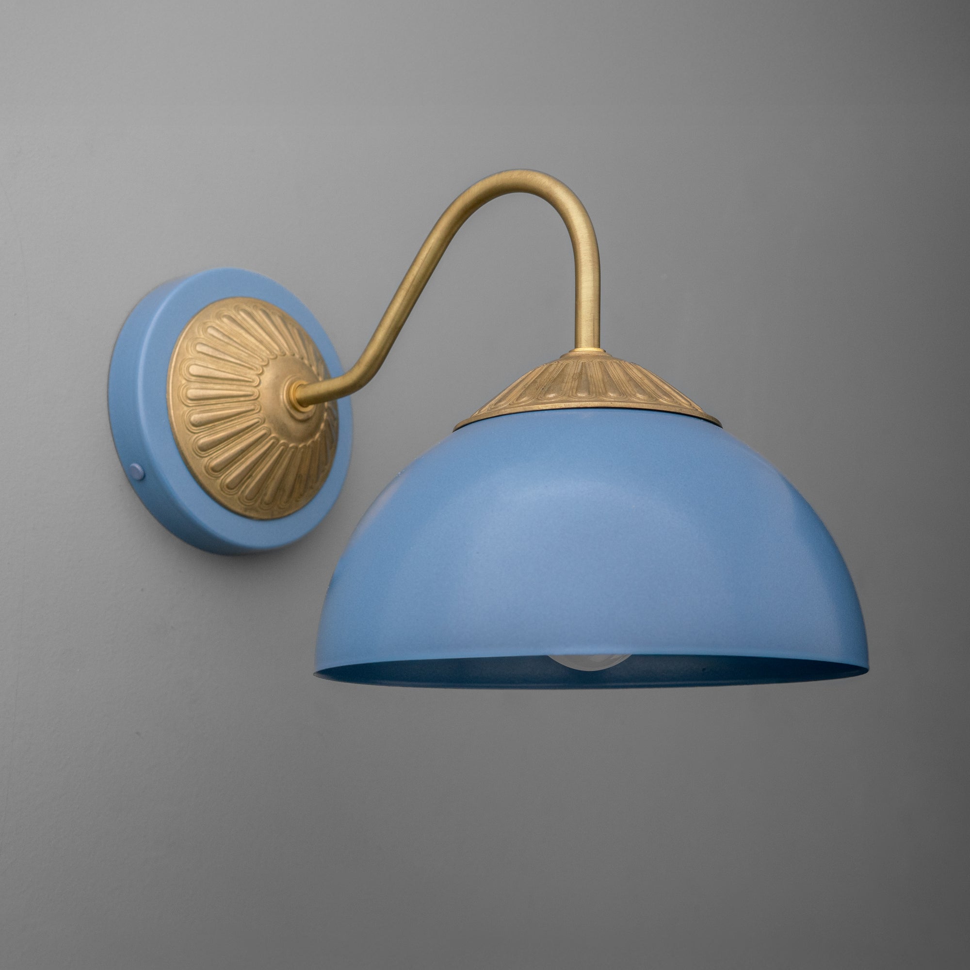 Raw brass sconce with a curved arm and periwinkle blue dome shade against a gray wall. - SCONCE MODEL NO. 9408
