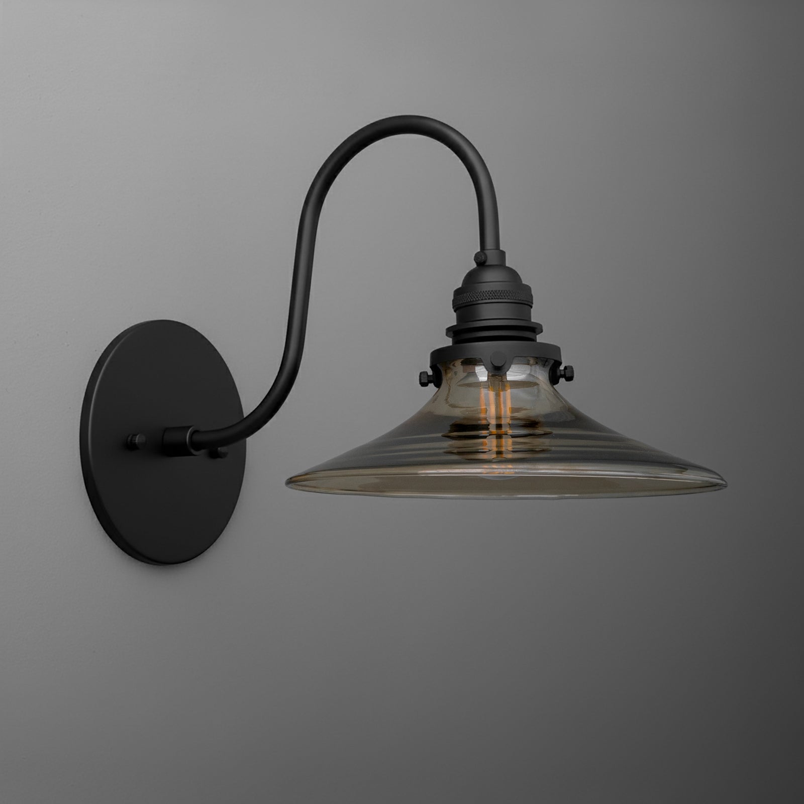 Black metal wall sconce with curved arm and wide clear glass shade revealing Edison bulb. - SCONCE MODEL NO. 3901