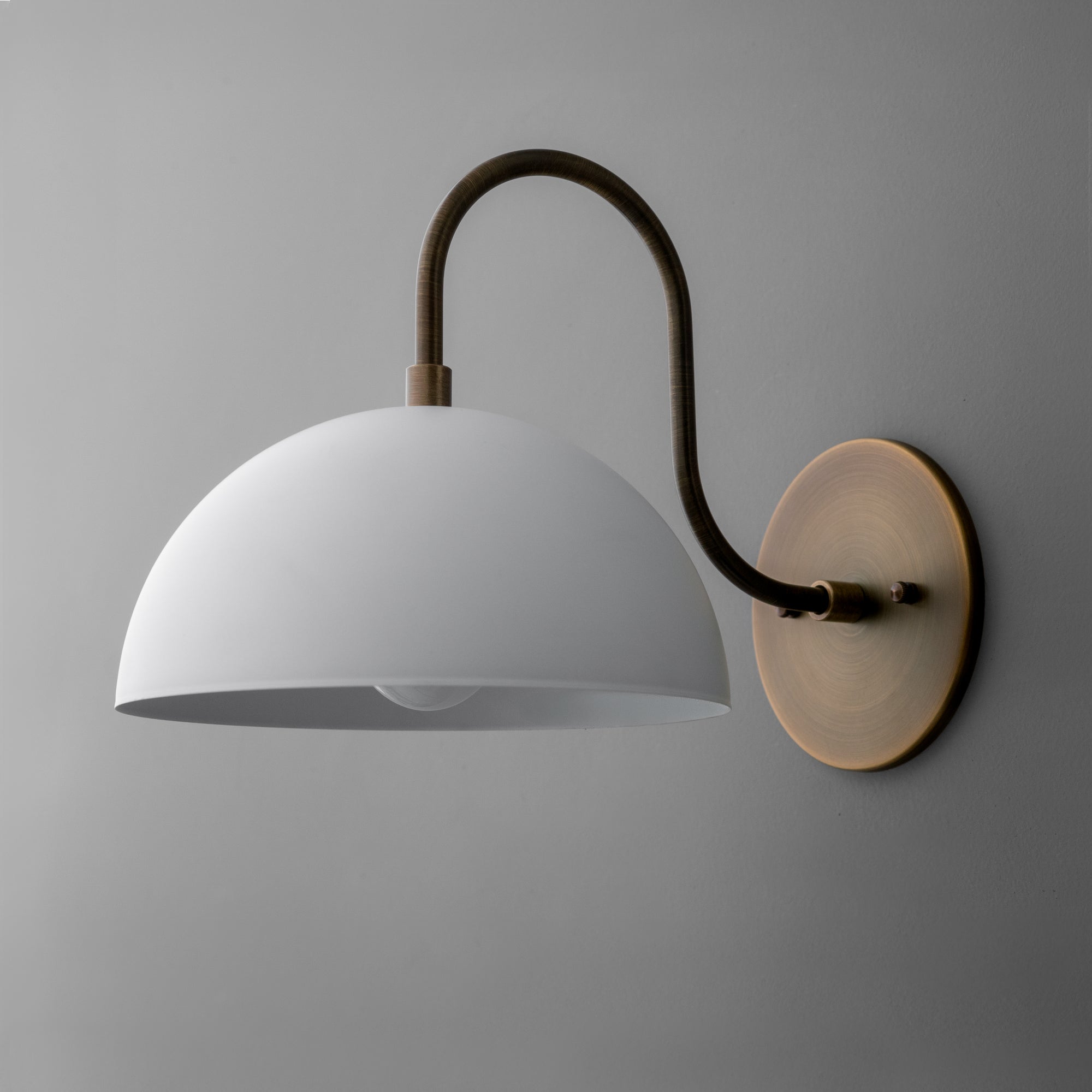 Antique brass wall sconce with curved arm and white dome-shaped shade. - SCONCE MODEL NO. 9092