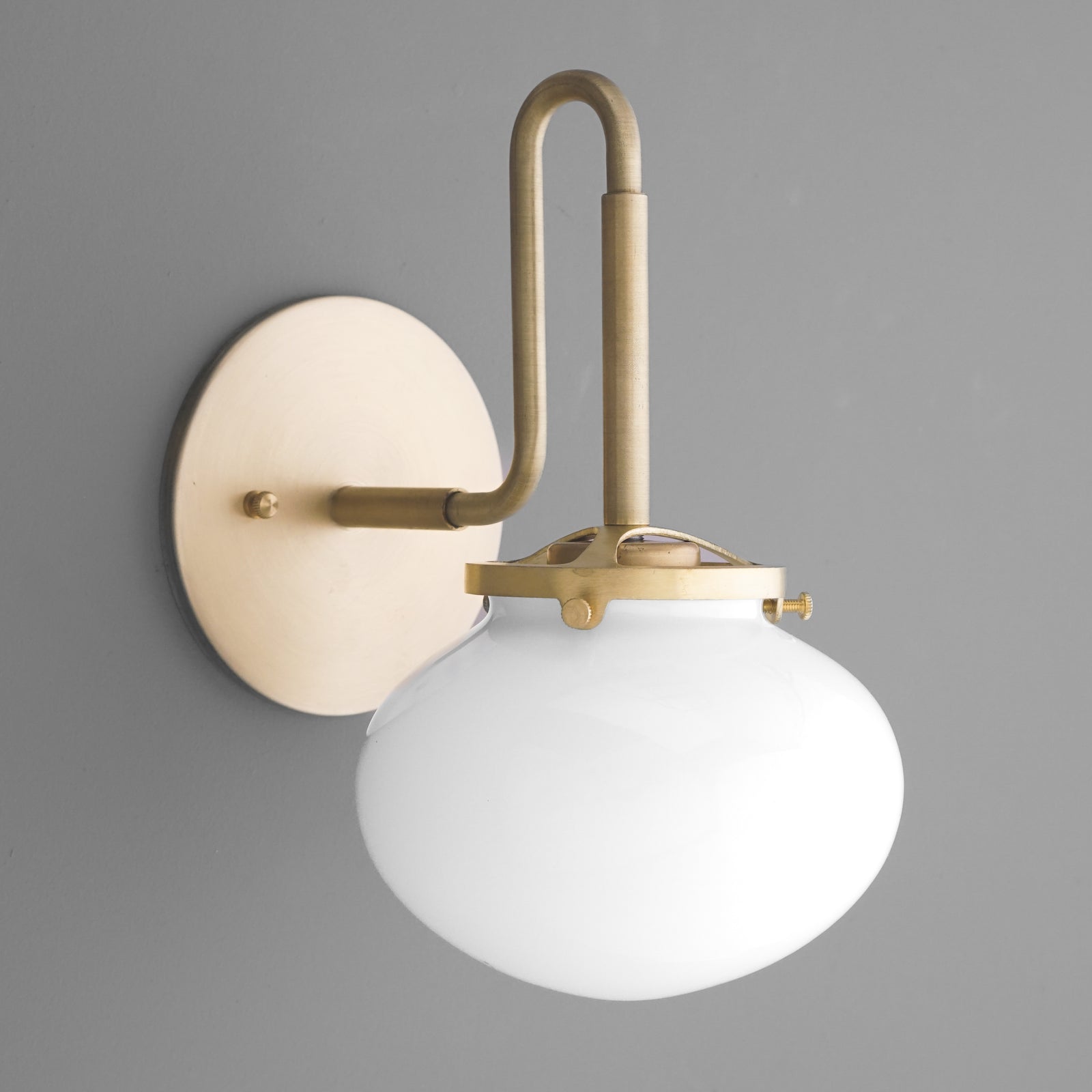 Brushed brass wall sconce with a curved arm and frosted white glass shade. - SCONCE MODEL NO. 9452