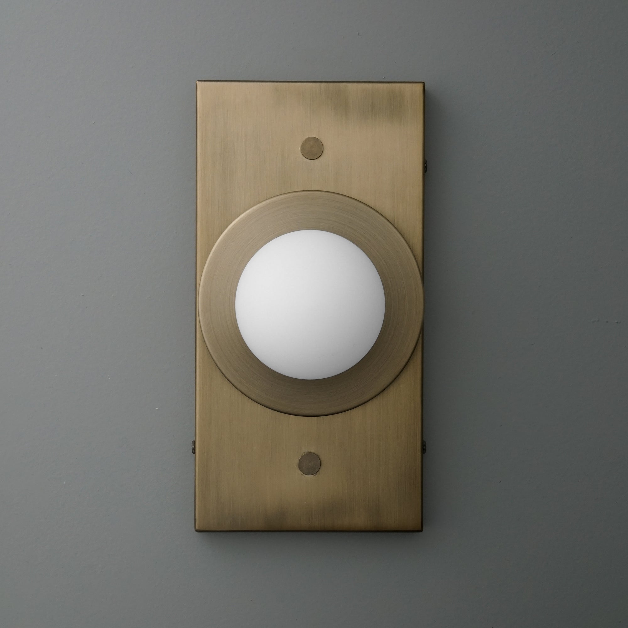 Minimalist antique brass wall sconce with frosted globe light on rectangular backplate. - SCONCE MODEL NO. 4474