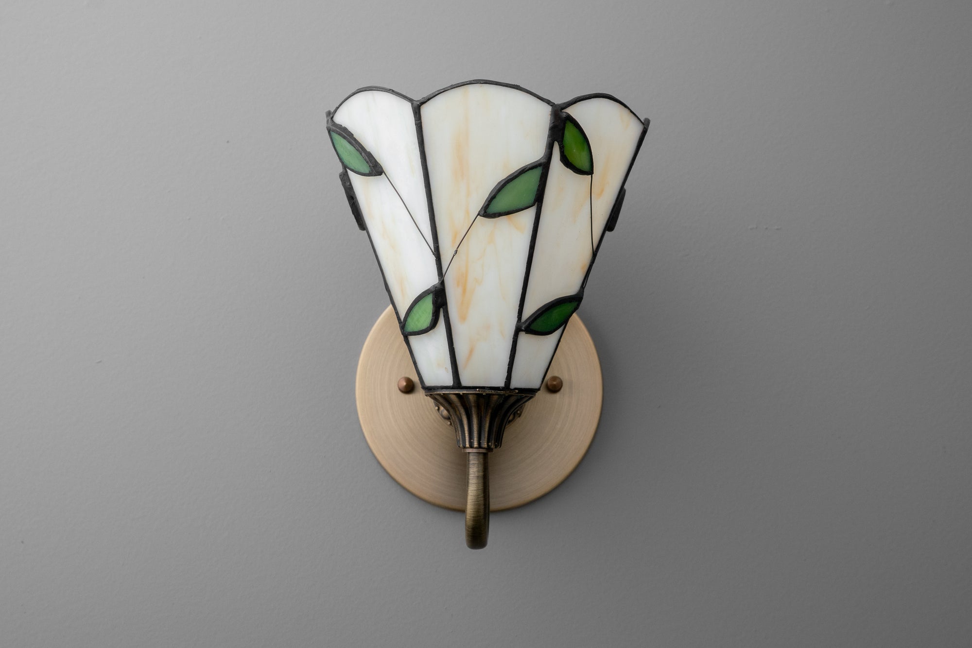 Antique brass wall sconce with stained glass shade featuring green leaf accents. - SCONCE MODEL NO. 8543