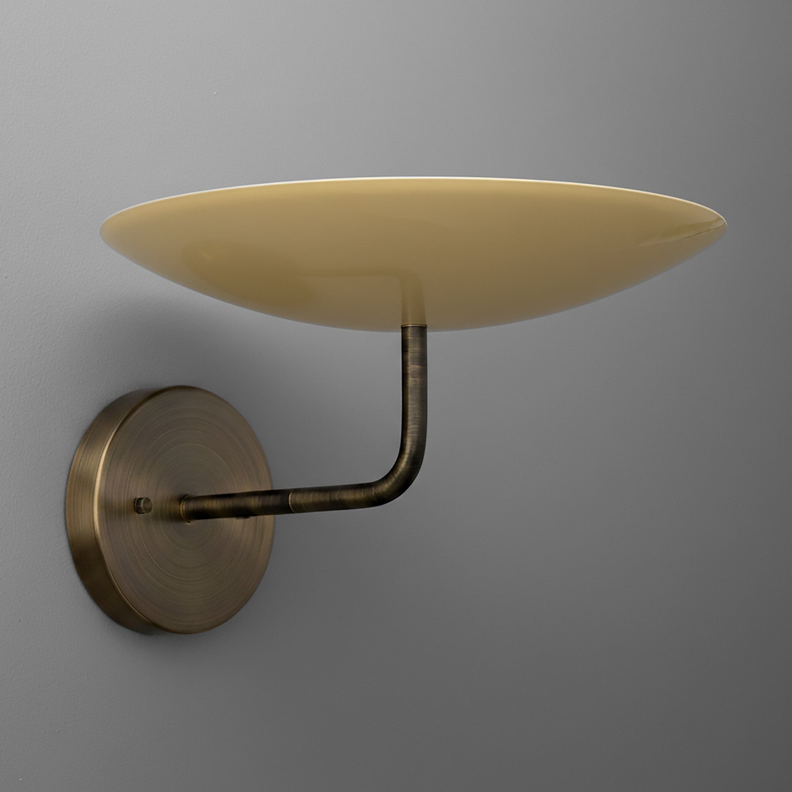 Bronze metal wall sconce with a round backplate and upward-facing shallow beige glass shade. - SCONCE MODEL NO. 1504
