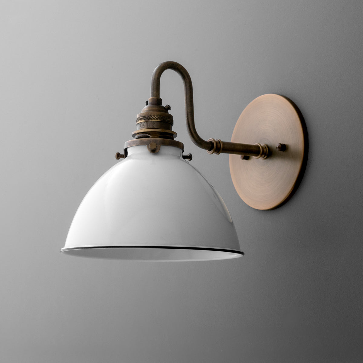 Wall-mounted sconce with a curved bronze arm and a white metal dome-shaped shade. - SCONCE MODEL NO. 2587