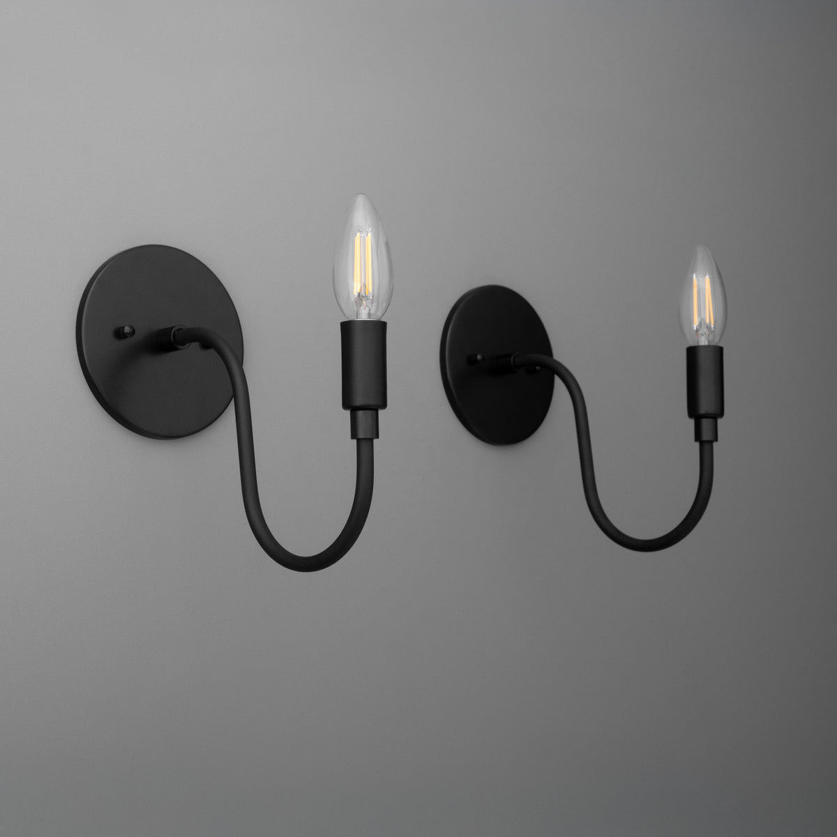Matte black metal wall sconces with curved arms and exposed bulb sockets. - SCONCE MODEL NO. 7321