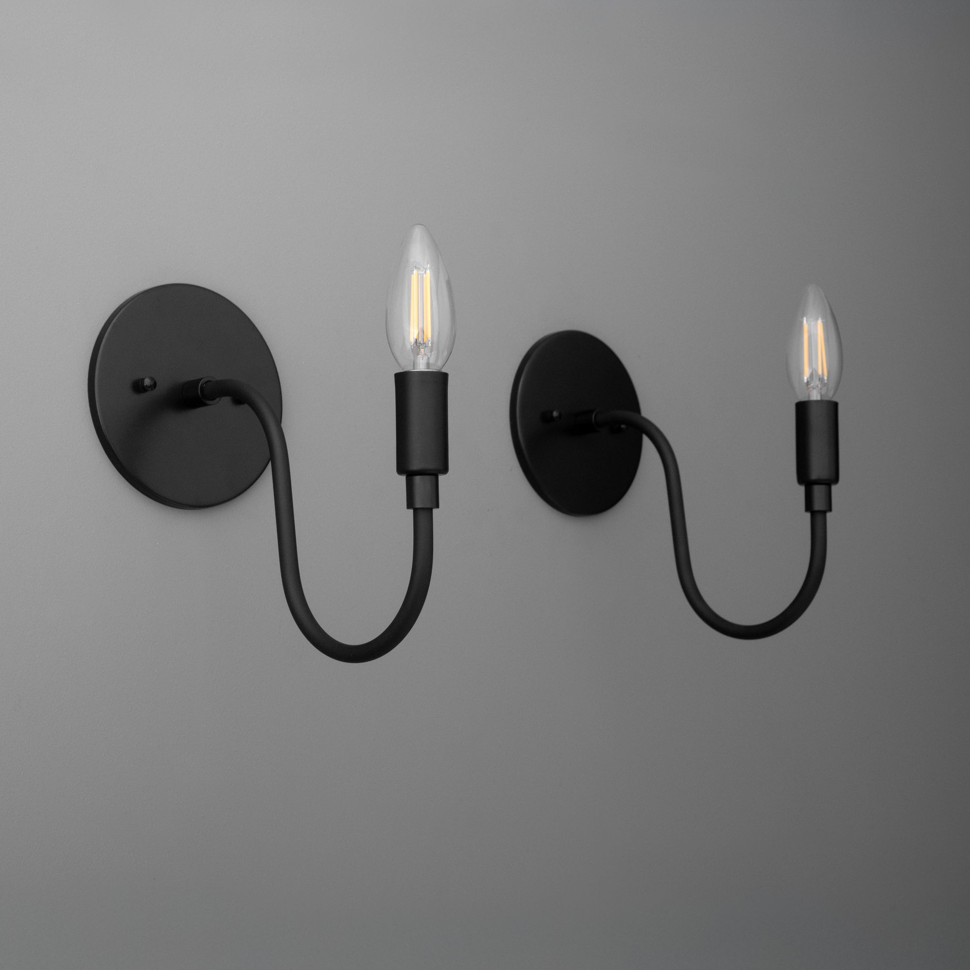 Matte black metal wall sconces with curved arms and exposed bulb sockets. - SCONCE MODEL NO. 7321