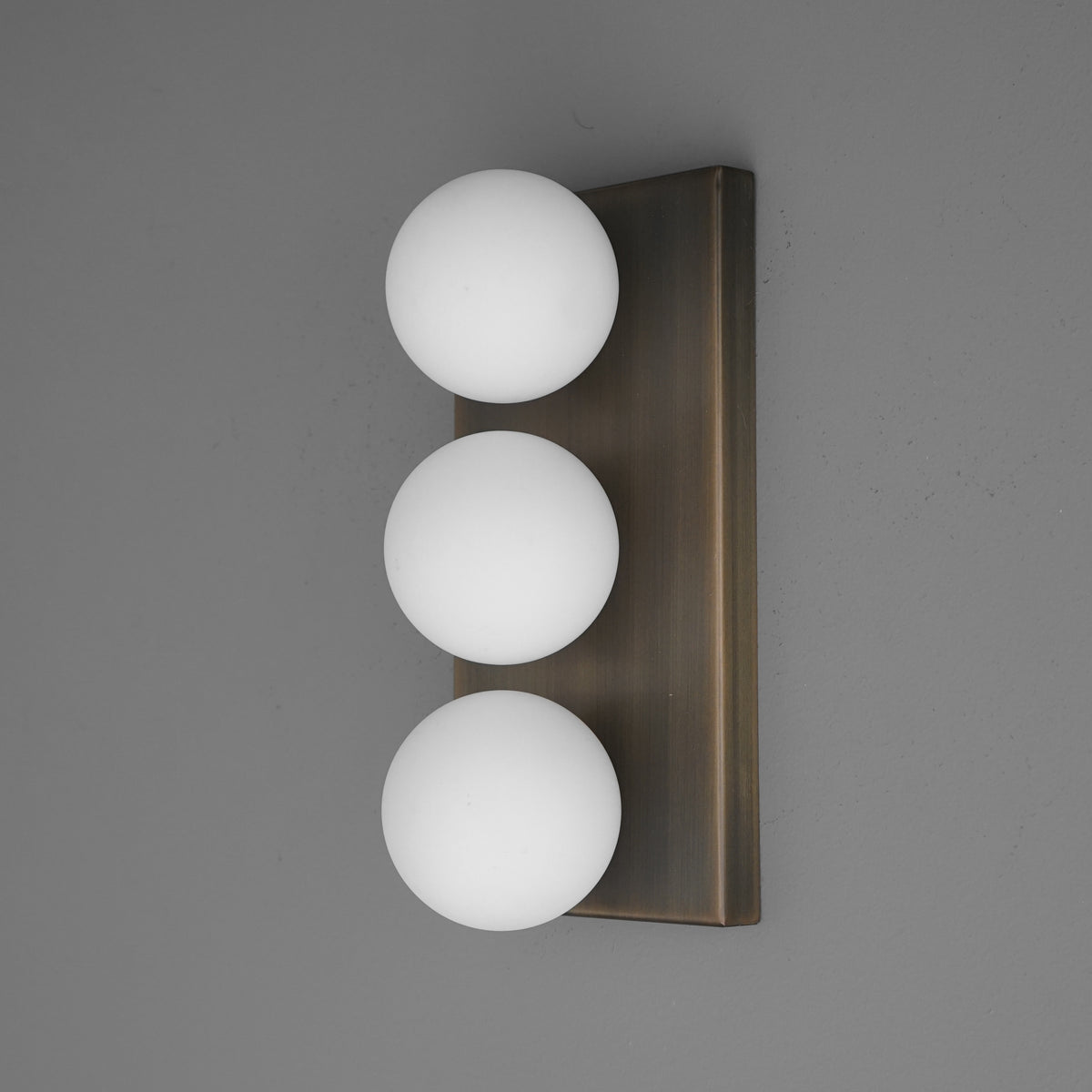 Wall sconce with three evenly spaced white glass globes on a vertical rectangular bronze base. - SCONCE MODEL NO. 2623