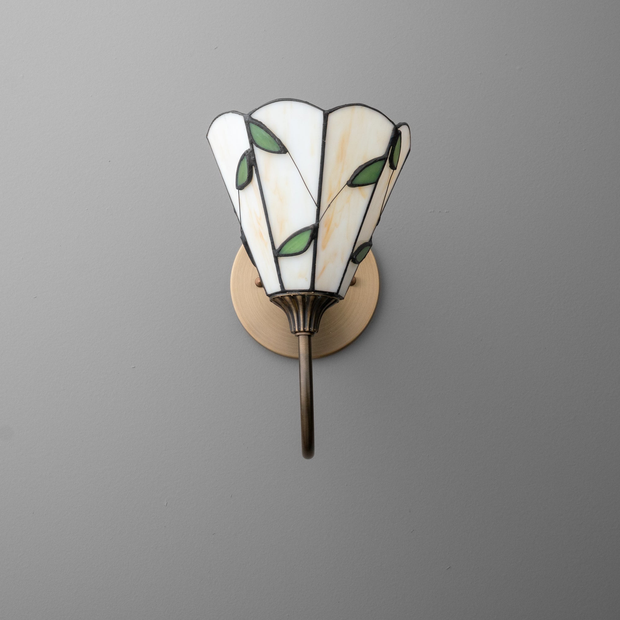 Art Deco-style wall sconce with stained glass shade featuring green leaf accents and antique brass base. - SCONCE MODEL NO. 1053