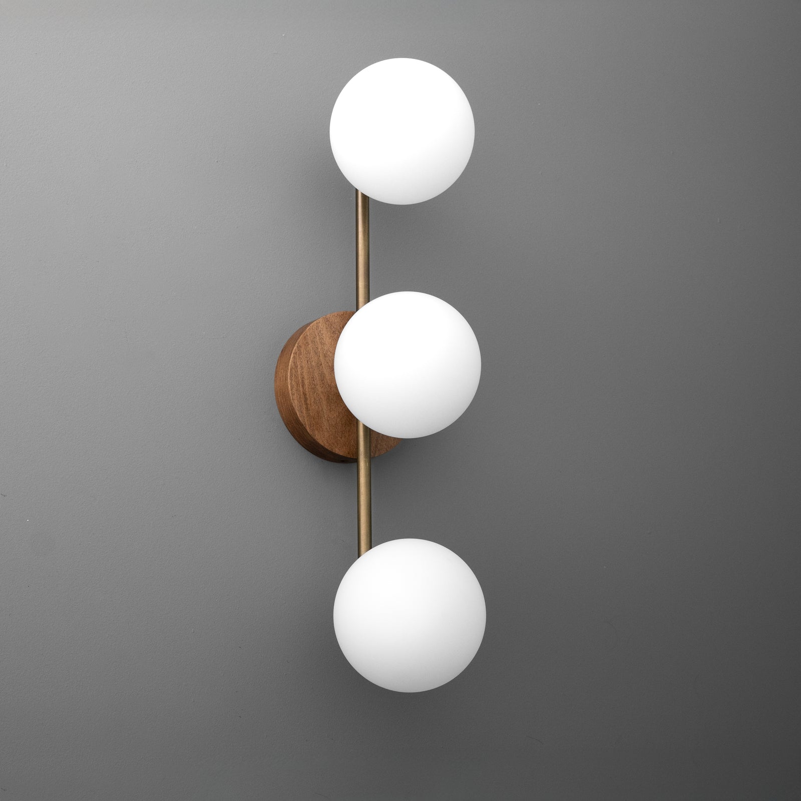 Wall sconce with three white frosted globe bulbs on a vertical brass rod and round wood base. - SCONCE MODEL NO. 6089
