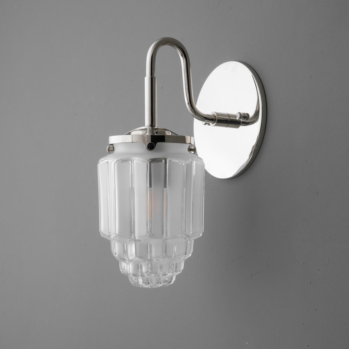 Polished chrome single-bulb sconce with tiered clear glass shade and curved arm. - SCONCE MODEL NO. 1035