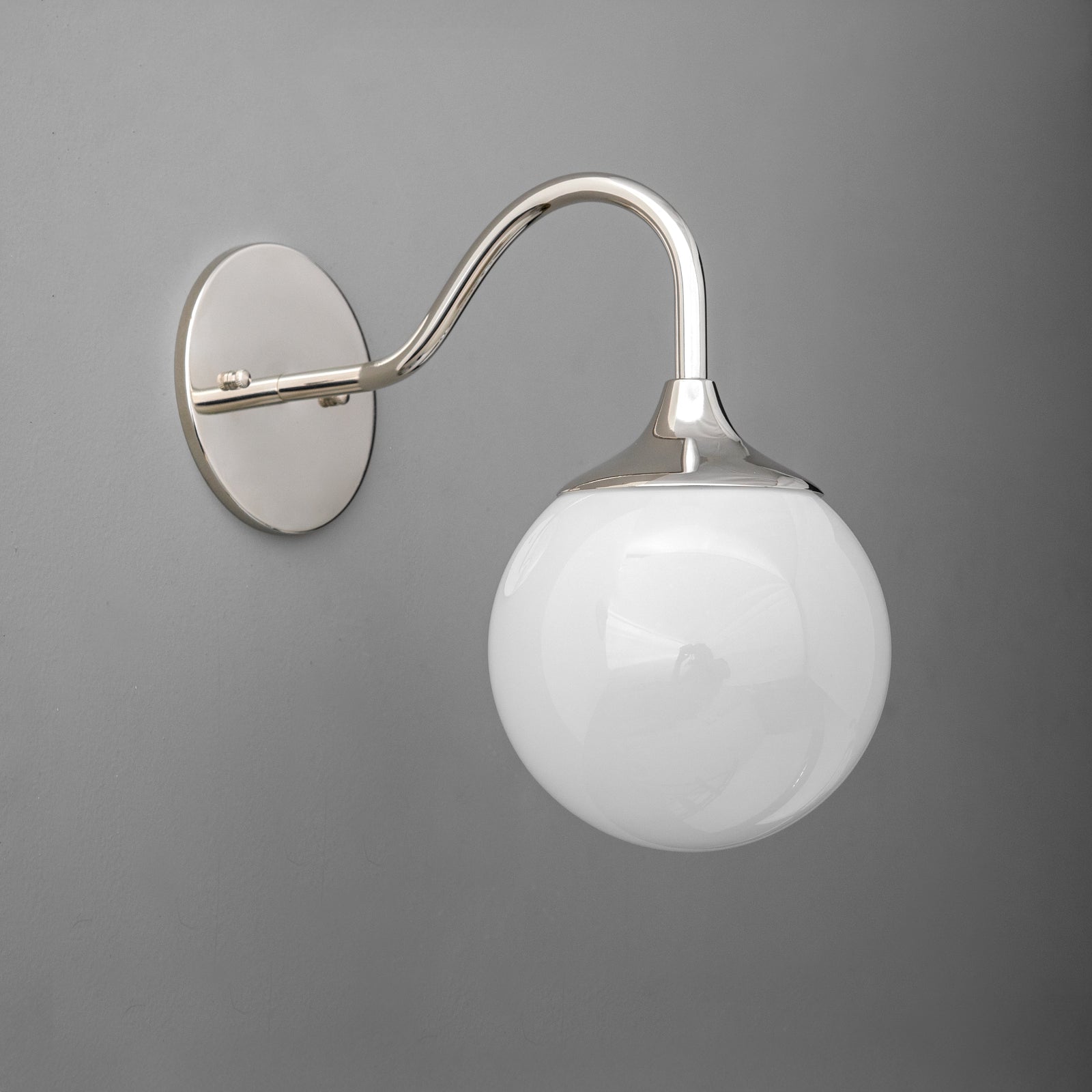 Polished nickel wall sconce with curved arm and white glass globe shade on gray background. - SCONCE MODEL NO. 8734
