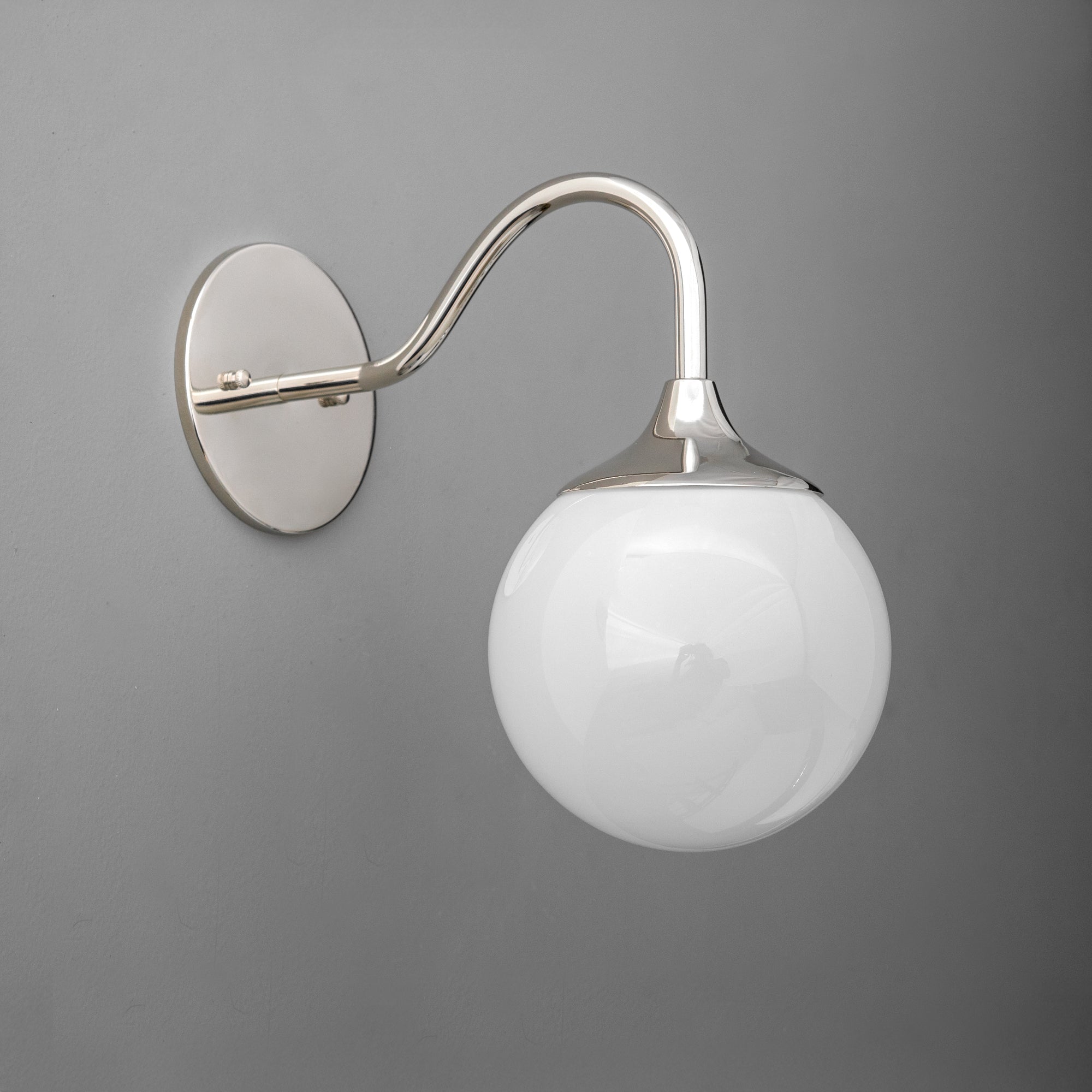 Polished nickel wall sconce with curved arm and white glass globe shade on gray background. - SCONCE MODEL NO. 8734