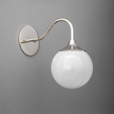 Polished nickel wall sconce with curved arm and white glass globe shade on gray background. - SCONCE MODEL NO. 8734