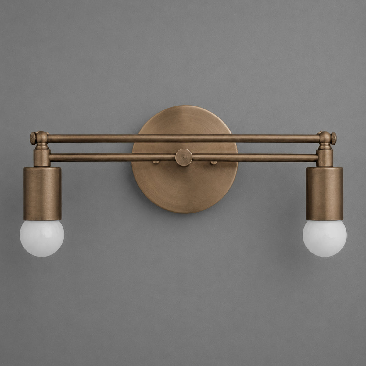 Two-bulb vanity light with antique brass finish and round wall mount against gray background. - VANITY LIGHT MODEL NO. 2360