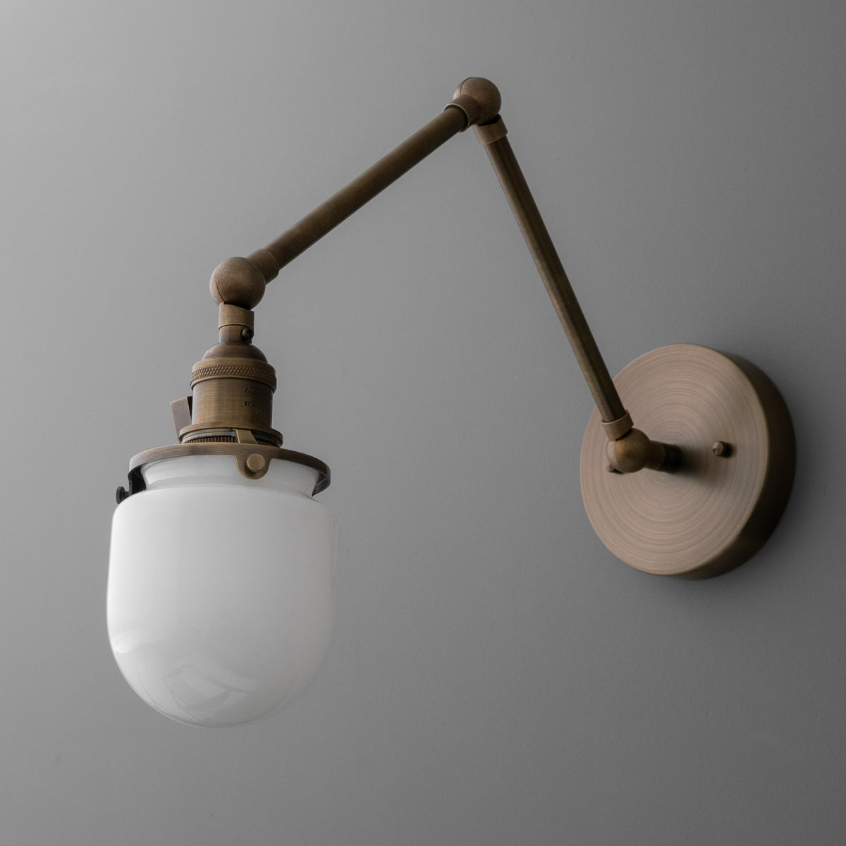 Wall-mounted adjustable arm sconce with round metal base and frosted white glass shade. - SCONCE MODEL NO. 7575