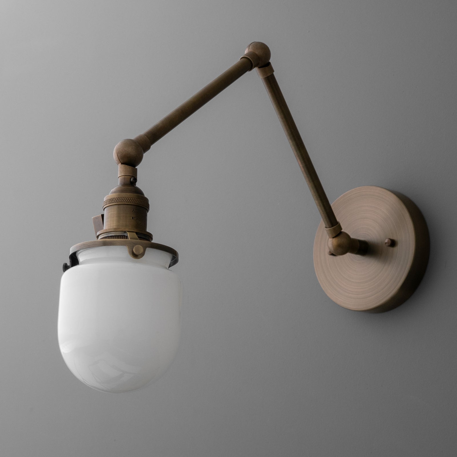 Wall-mounted adjustable arm sconce with round metal base and frosted white glass shade. - SCONCE MODEL NO. 7575