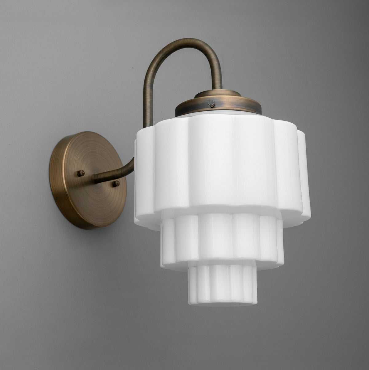 Antique bronze wall sconce with tiered white frosted glass shade and curved arm. - SCONCE MODEL NO. 1095