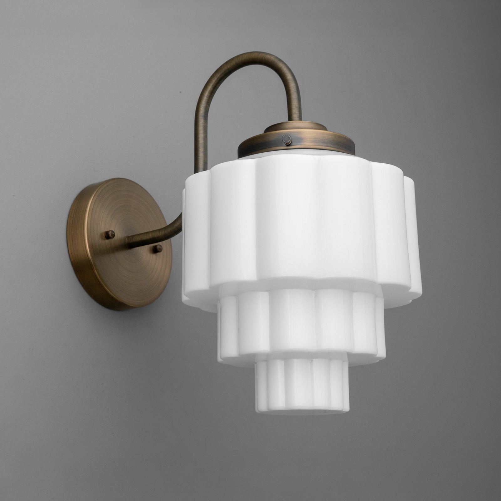 Antique bronze wall sconce with tiered white frosted glass shade and curved arm. - SCONCE MODEL NO. 1095