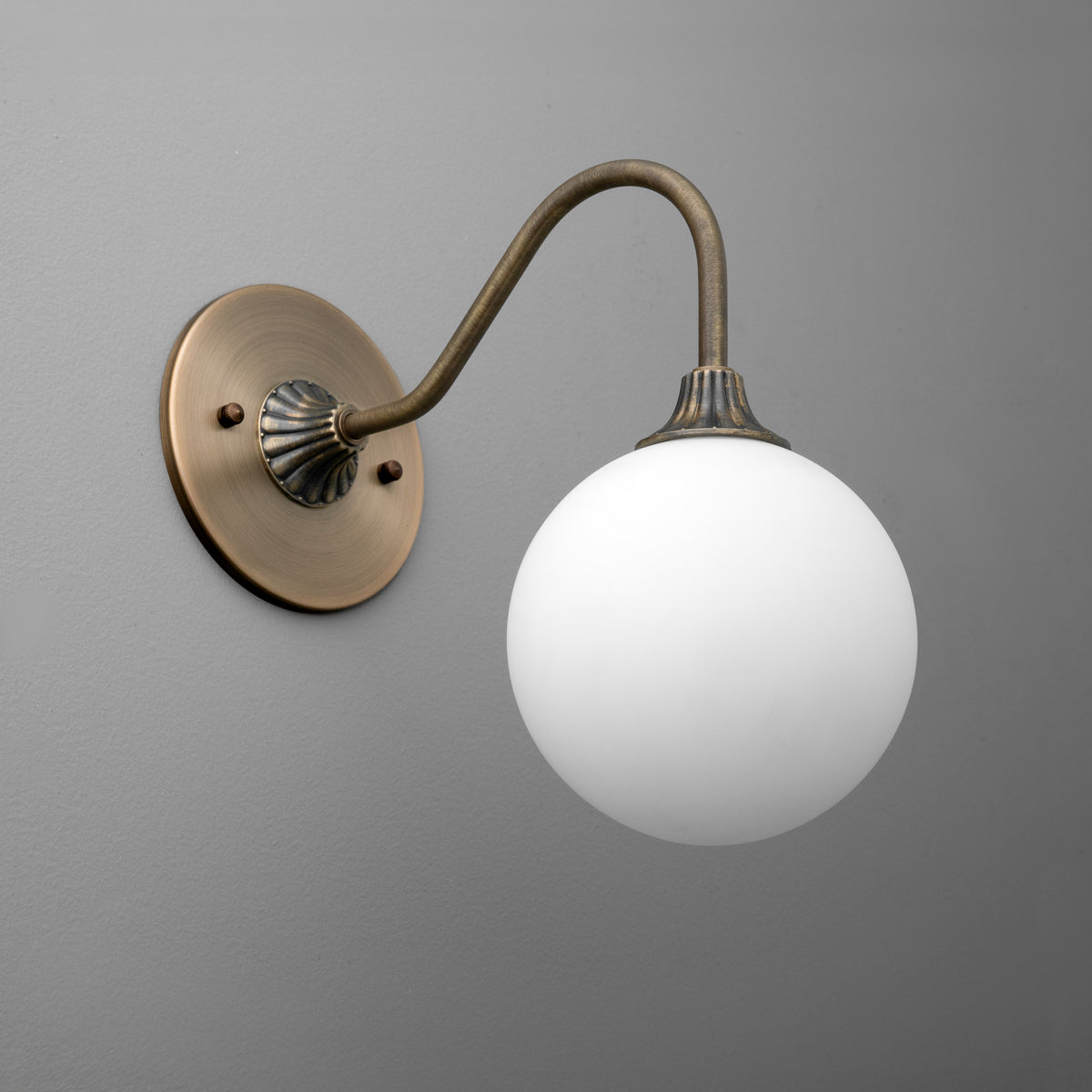 Antique brass wall sconce with curved arm and white frosted glass globe shade. - SCONCE MODEL NO. 8263