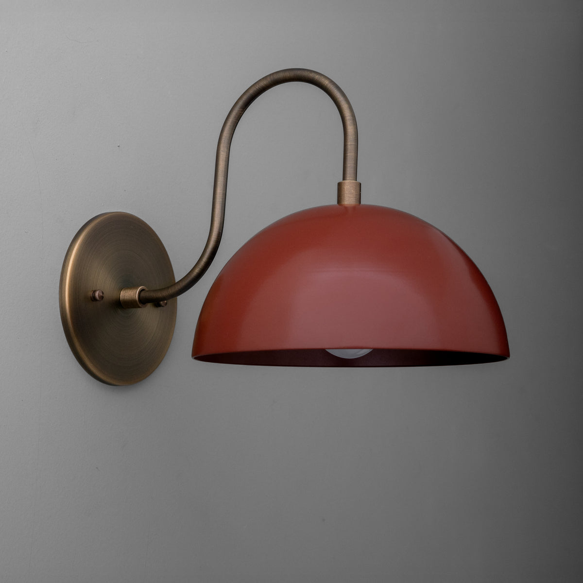 Antique brass wall sconce with curved arm and dome-shaped brick red metal shade. - SCONCE MODEL NO. 9092