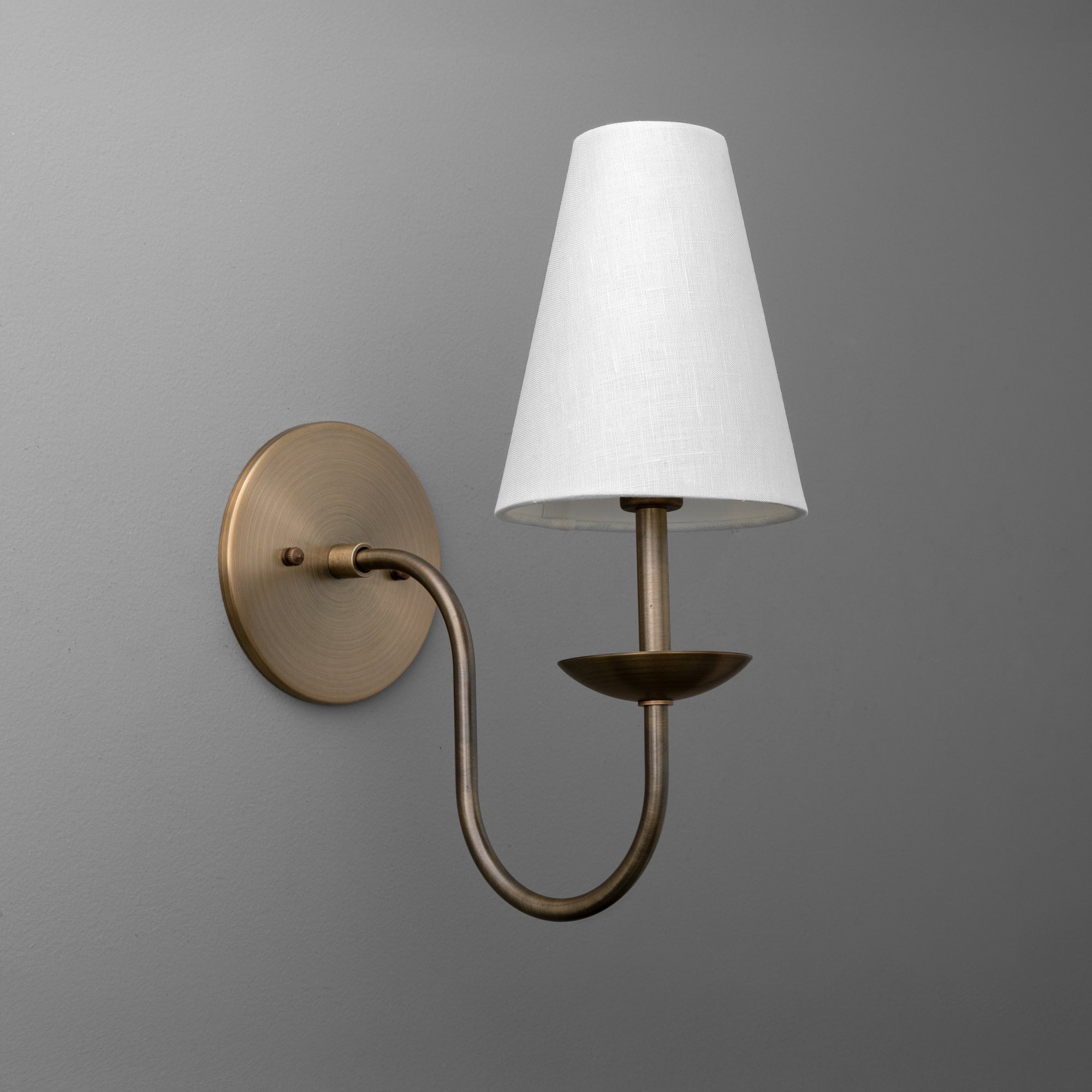 Antique brass wall sconce with curved arm and white tapered fabric shade. - SCONCE MODEL NO. 9867