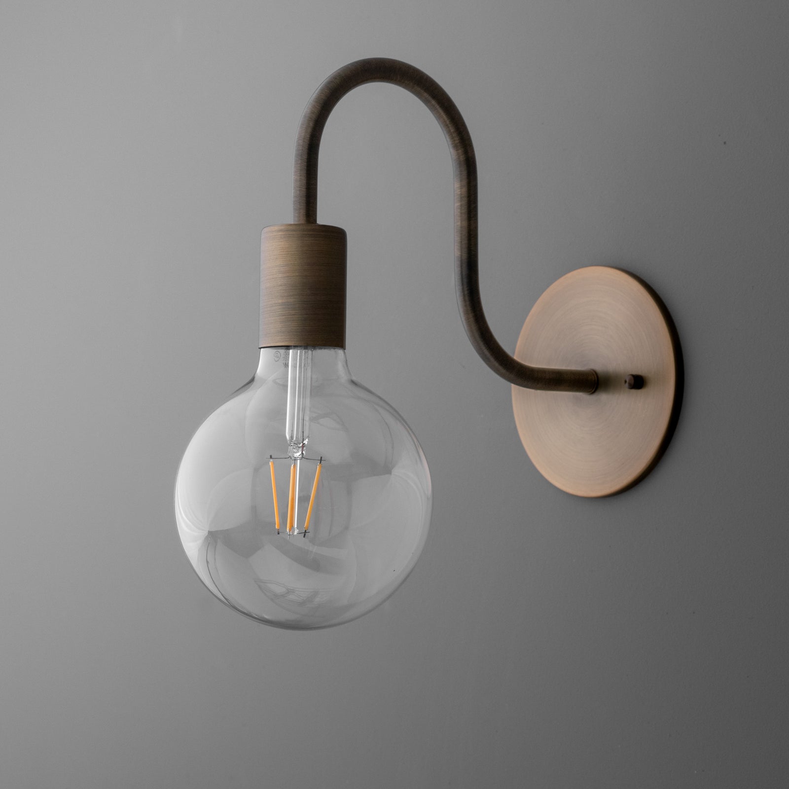 Matte bronze single-bulb wall sconce with round backplate and curved arm holding a clear globe bulb. - SCONCE MODEL NO. 4753