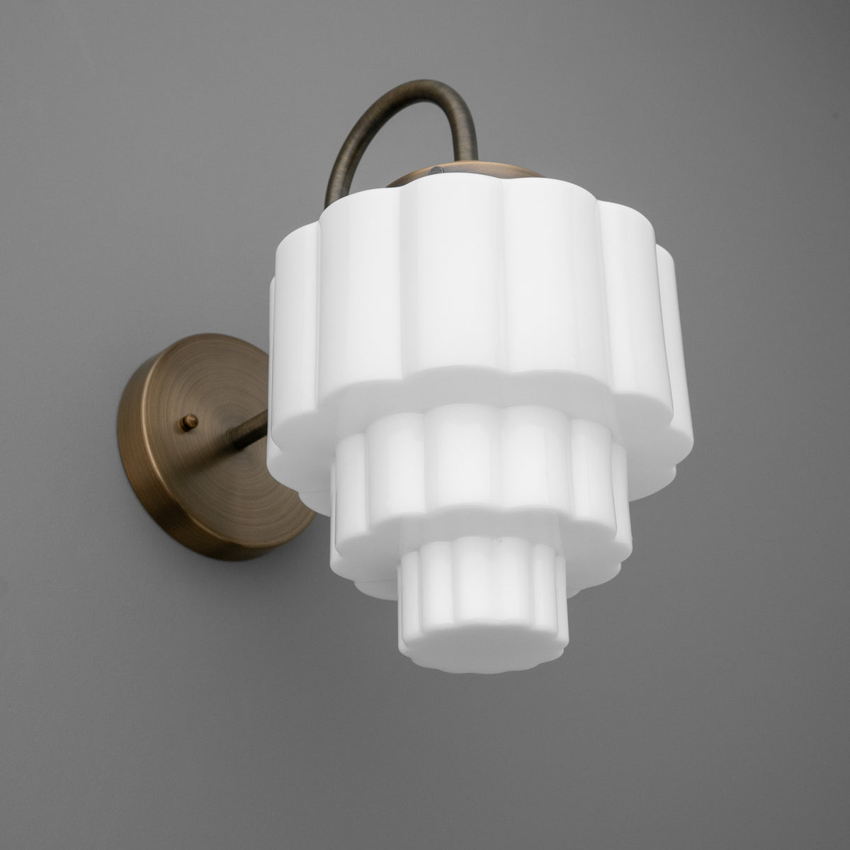 Wall-mounted sconce with tiered white glass shade and antique bronze metal base and arm. - SCONCE MODEL NO. 1095