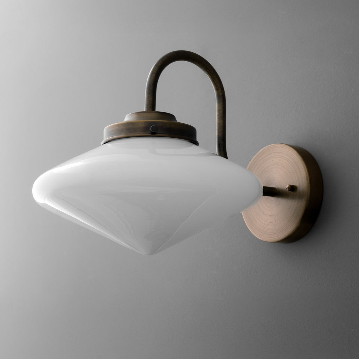 Wall sconce with frosted white glass shade and curved bronze arm mounted on round bronze base. - SCONCE MODEL NO. 1021