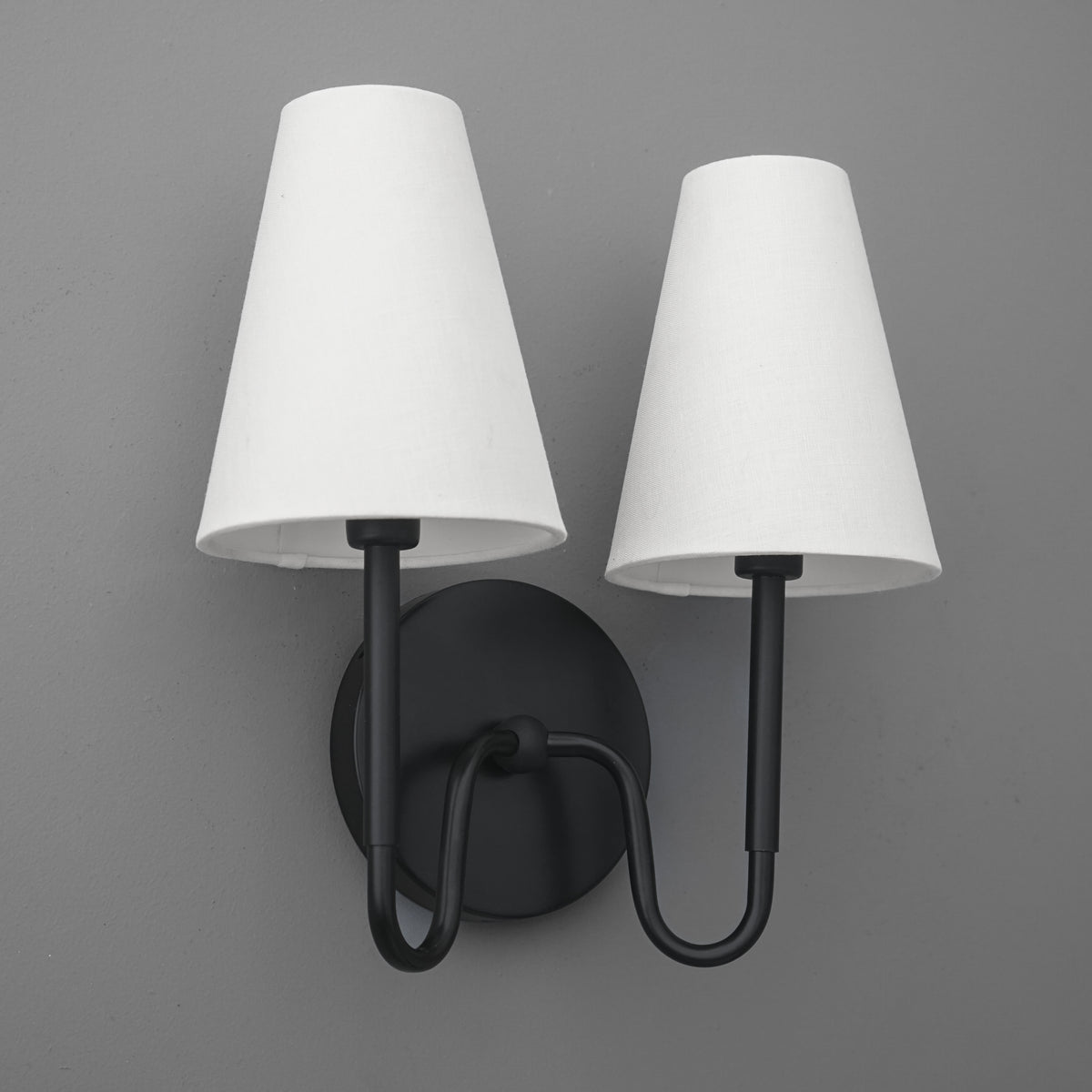 Black metal double-arm wall sconce with two white tapered fabric shades. - SCONCE MODEL NO. 5265