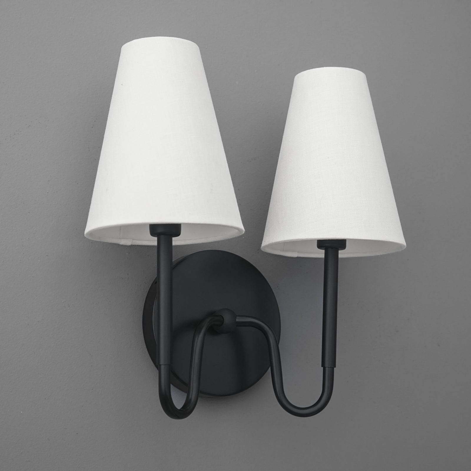 Black metal double-arm wall sconce with two white tapered fabric shades. - SCONCE MODEL NO. 5265