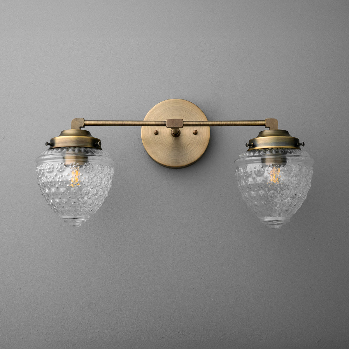 Two-bulb brass vanity light with ornate clear glass shades and round wall mount. - VANITY LIGHT MODEL NO. 1155