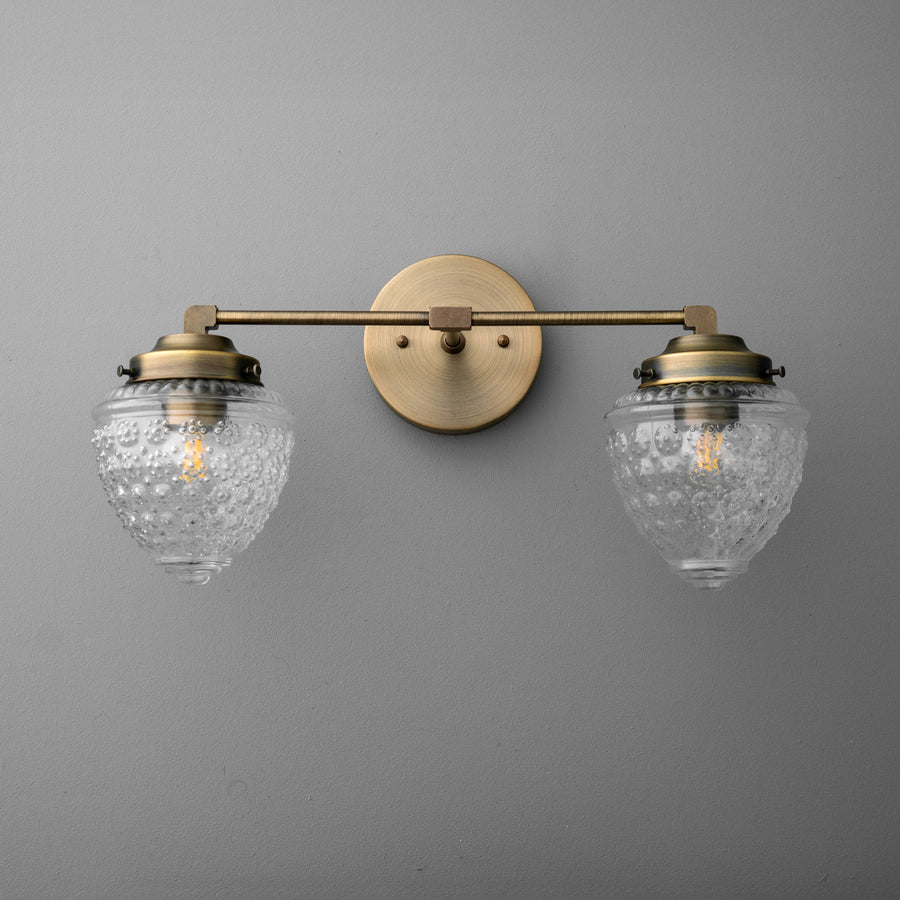 Two-bulb brass vanity light with ornate clear glass shades and round wall mount. - VANITY LIGHT MODEL NO. 1155