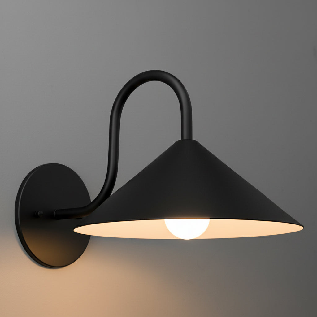 Black metal wall sconce with conical shade and curved arm, warm light bulb visible underneath. - SCONCE MODEL NO. 1015