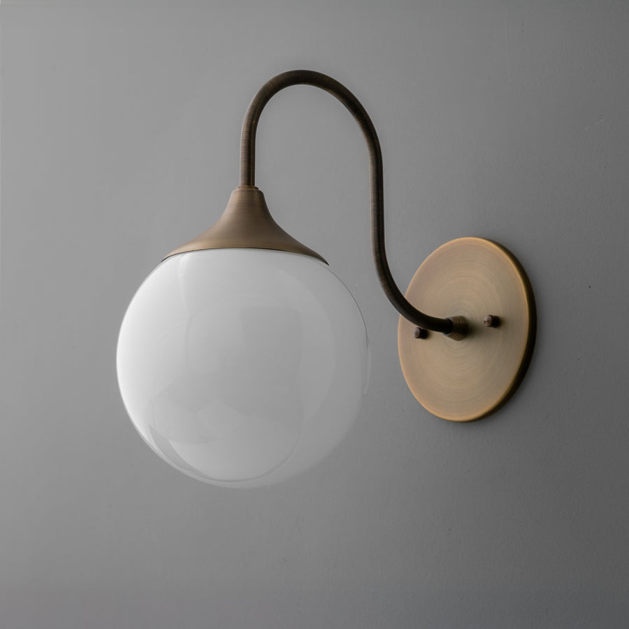 Wall sconce with curved antique brass arm and frosted white glass globe shade on round brass base. - SCONCE MODEL NO. 3961