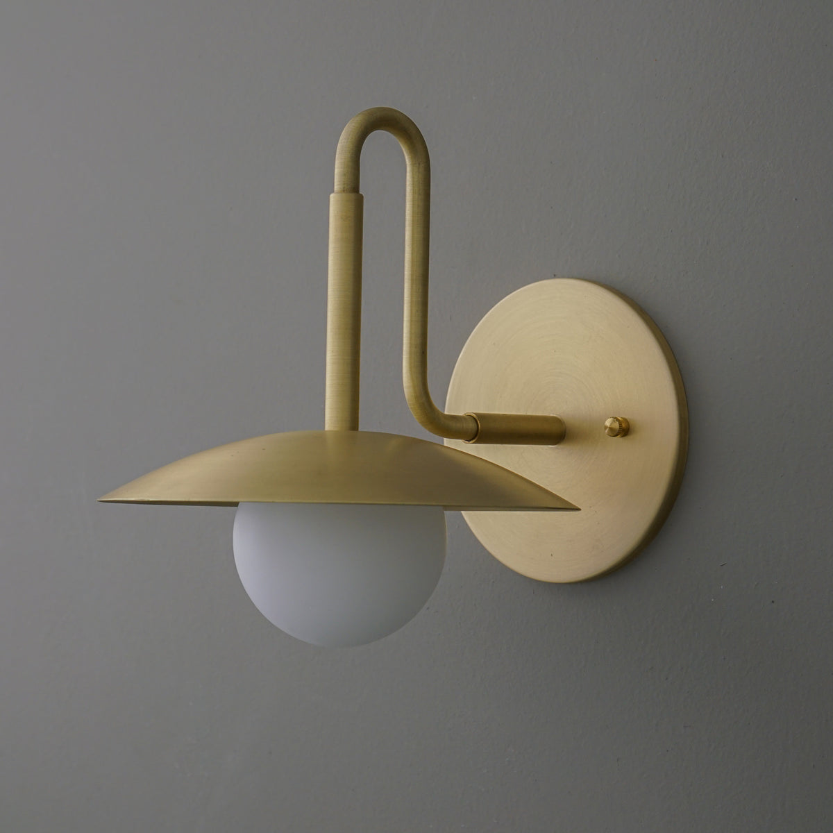 Matte gold metal wall sconce with a flat dome shade and frosted glass globe bulb. - SCONCE MODEL NO. 1013