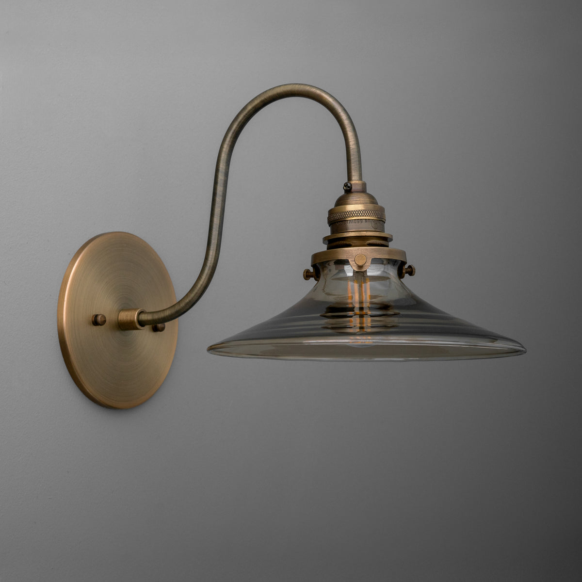 Antique brass wall sconce with curved arm and clear glass wide conical shade. - SCONCE MODEL NO. 3901