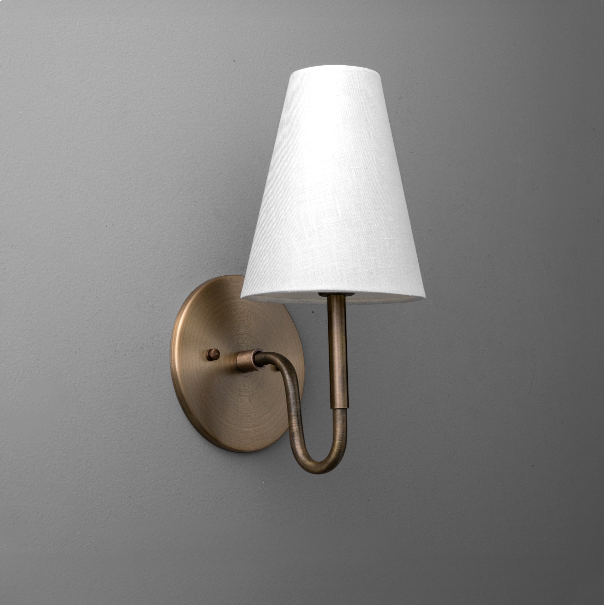 Antique brass wall sconce with curved arm and white tapered fabric shade. - SCONCE MODEL NO. 1699