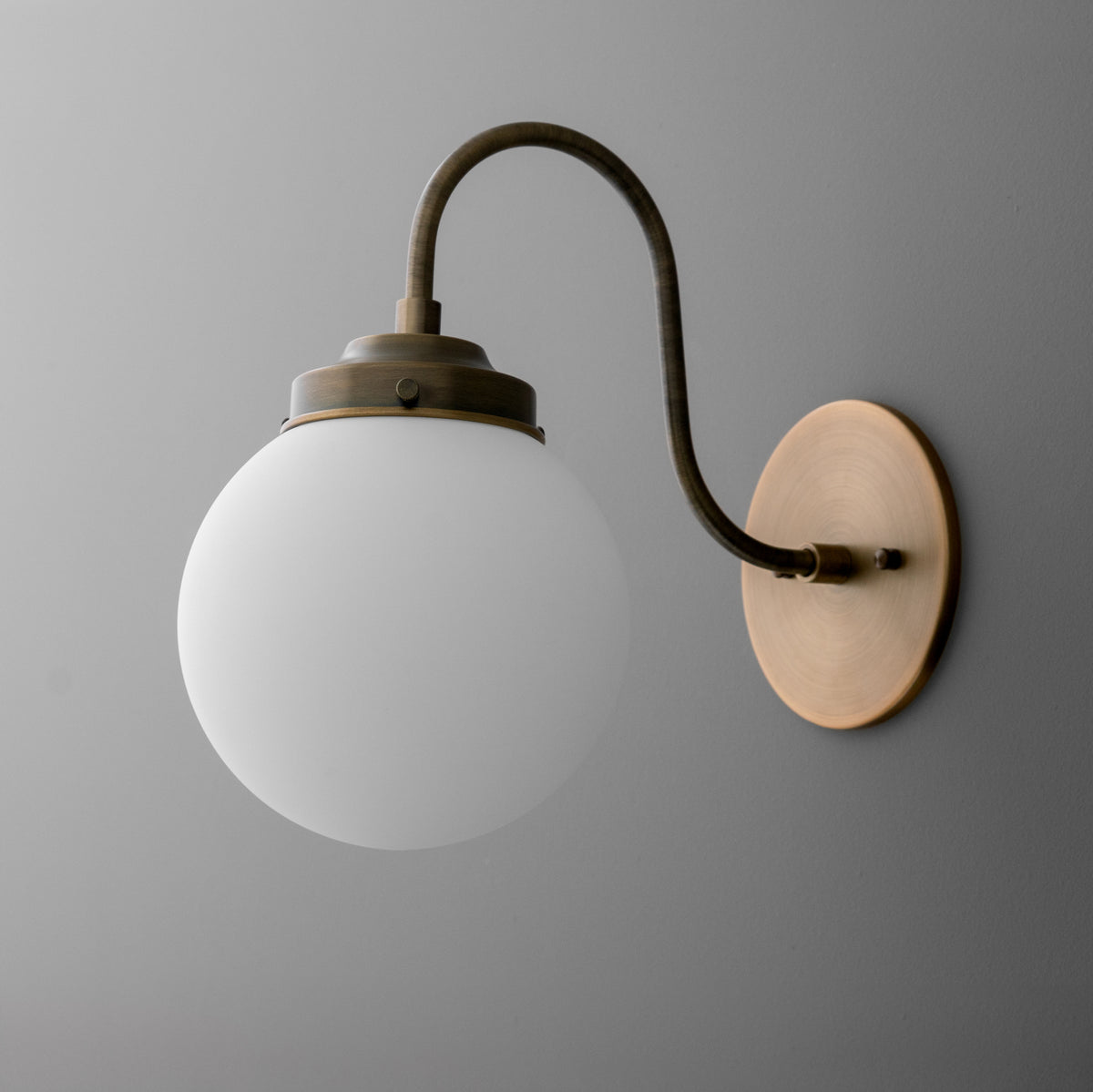 Wall-mounted sconce with matte white glass globe and curved antique brass arm on round base. - SCONCE MODEL NO. 1886